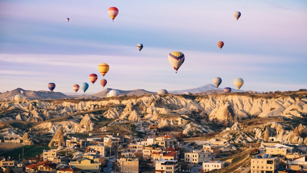 Colorful hot air balloons flying over the city at Cappadocia, Turkey. Volcanic mountains in Goreme national park in the morning.