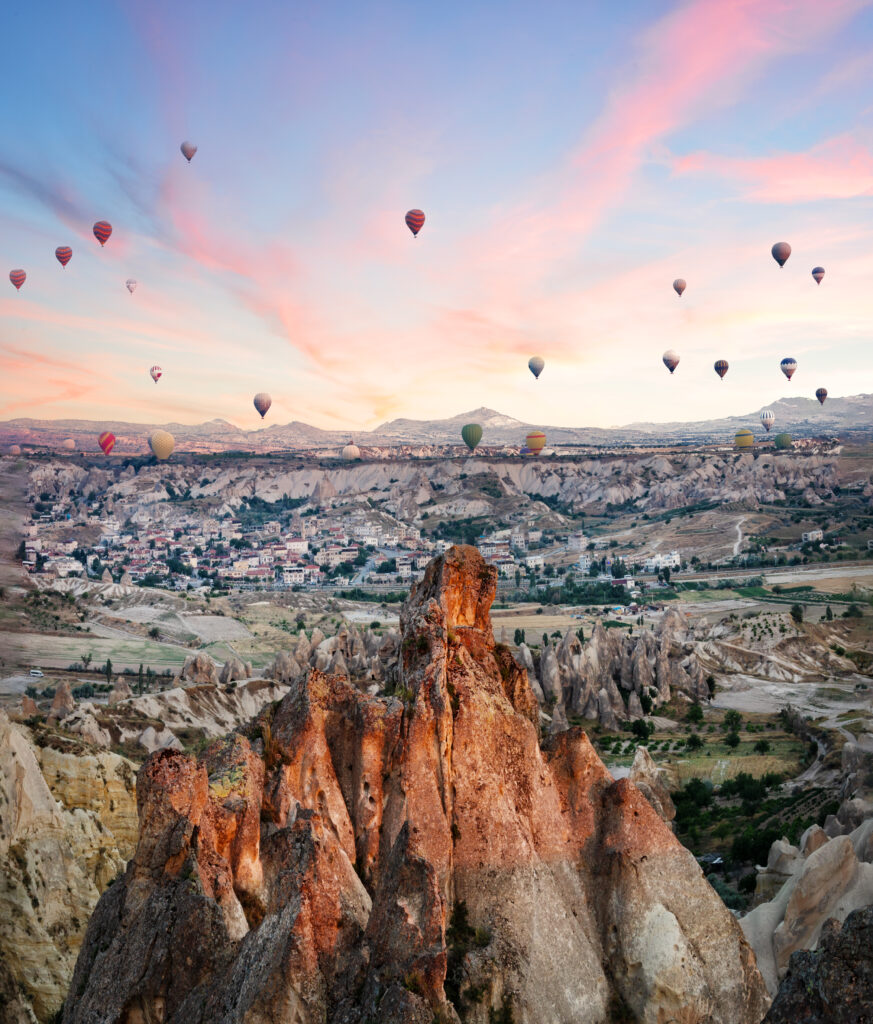 Balloons over the rocks of Cappadocia in the early morning. Pink dawn. Goreme, Turkey. Trade marks removed